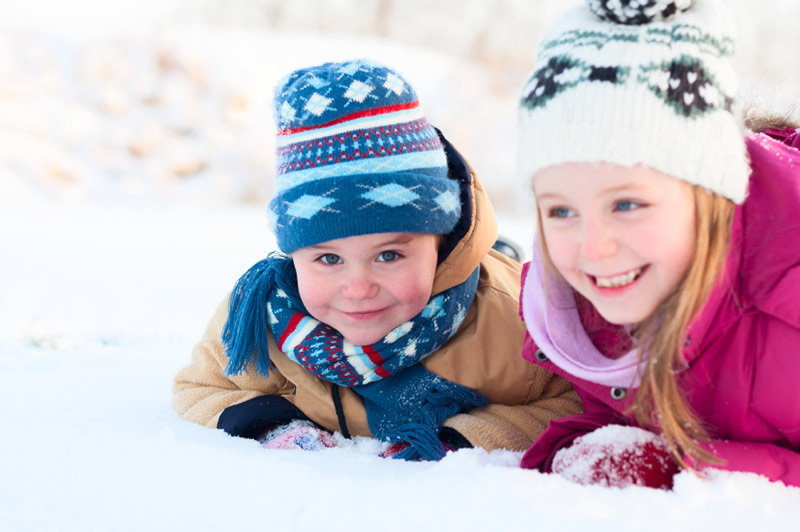 Jente med lillebror i snøen, smiler