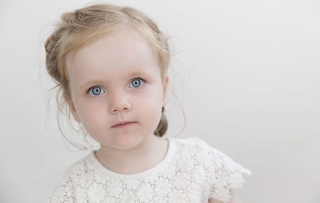 En jente med store blå øyne og ser alvorlig ut